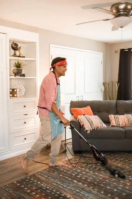 Woman wrapping a sofa with plastic for moving in a bright living room.